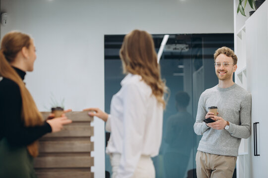 Business people talking while holding coffee cups at office cafeteria - Powered by Adobe