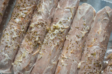 Raw seasoned sausages on baking tray closeup