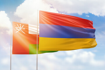 Sunny blue sky and flags of armenia and oman