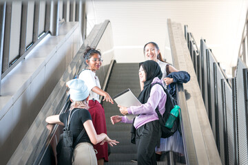 Group of young multi-racial female students laughing while going up the escalator.