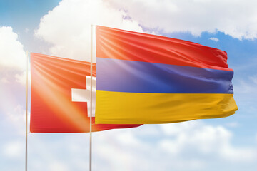 Sunny blue sky and flags of armenia and switzerland