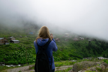 Naklejka premium Rize, Turkey - July 2016: A young girl photographing with a mobile cell phone on a high plateau. Photo was taken in plateau in Rize, Karadeniz region of Turkey. 
