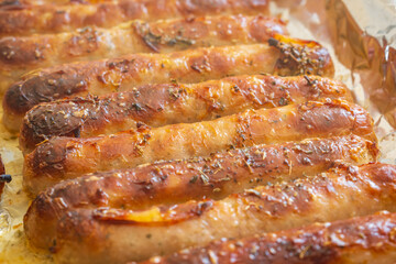 Piping hot sausages on baking tray closeup