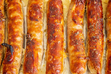 Piping hot sausages on baking tray closeup