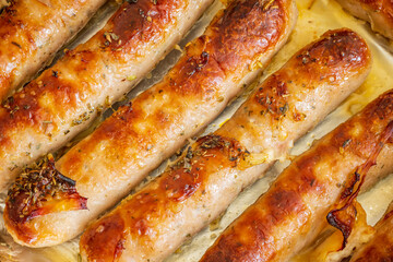 Piping hot sausages on baking tray closeup