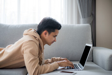 Young man  sitting on at home and using laptop computer to communicate with friends. He was happy to talk to his friends and he felt that technology made it easier to communicate over distance.