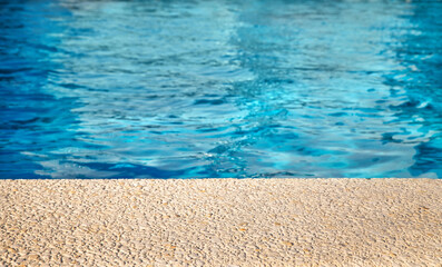 Pool side surface with blurred pool water background, selective focus. Product placement, copy space