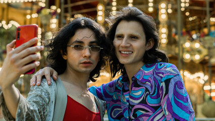 Two people from the Lgbt community in a park taking a selfie and smiling at a fair.
