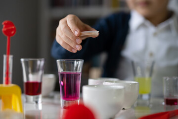 Close up on hand of One small caucasian boy scientist five years old sitting at the table playing with chemistry equipment toy preforming experiment learning and education concept front view