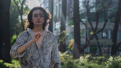 Very handsome gay person walking on the streets in a park in the city, with a bright background, wearing sunglasses.	