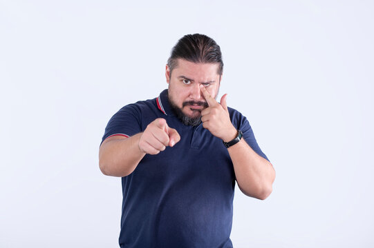 A emotionally hurt man points and puts the blame on someone while wiping a tear from his eye. Slightly comical and funny expression.