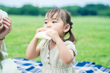 mother and her daughter eating sandwiches in the park