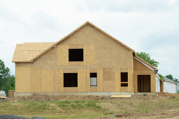 A residential house construction project showing plywood roof and dormer sheathing and oriented...