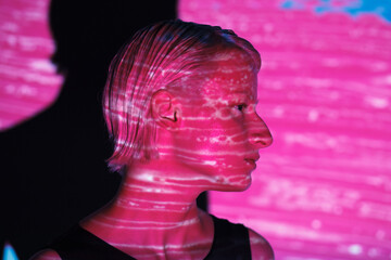 fashion androgyne woman with projection of neon pink stripe on face