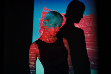 fashion androgyne woman with projection of neon pink stripe on face