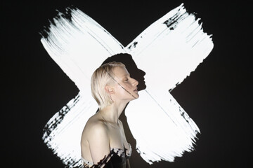 fashion androgyne woman with projection of white cross shape isolated on black background - Powered by Adobe