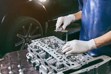 Auto mechanic working in garage. Repair service.  opened automobile engine cylinder head for...