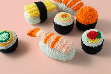 Assorted set of maki sushi rolls and nigiri sushi handmade in crochet and colored wool. Sushi set isolated on a pink background. Sushi crochet amigurumi © EdwinGrandas
