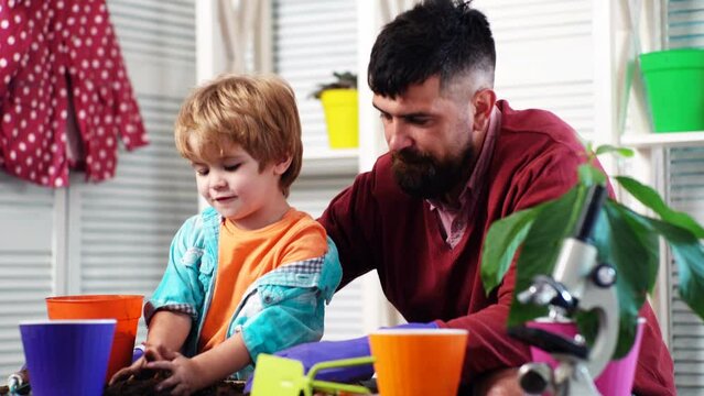 Father ans son growing plant in pot. Family holiday and togetherness. Little cute boy helps his parent. Happy family planting sprout in a plant pot.