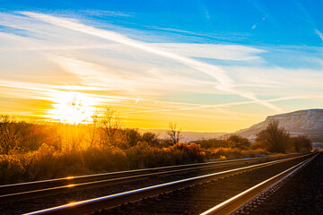 Fototapeta na wymiar Railroad sunset in the rocky mountains with blue and orange skies