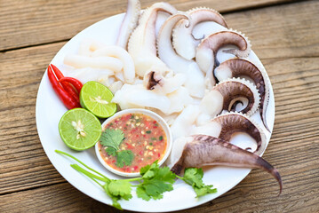 seafood plate squid food on white plate, Fresh squid cooked boiled steam with vegetable salad lemon lime and seafood sauce chili sauce serve on table, octopus tentacles cuttlefish ocean gourmet