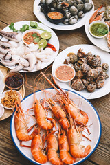 seafood plate with shrimp shellfish crab squid cockle spotted babylon with seafood sauce chili lemon lime serve on dining table, shrimps prawns seafood buffet menu cooked food - top view