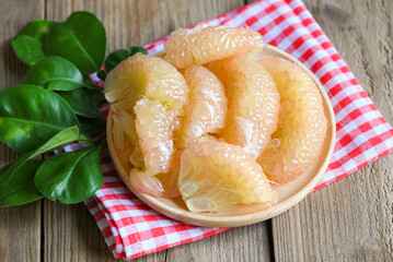 pomelo fruit on wooden plate, fresh green pomelo peeled on wooden and green leaf frome pomelo tree...