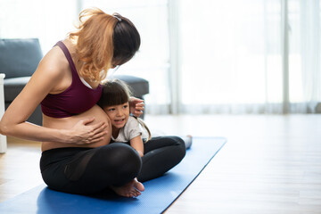 Asian young woman pregnant and little girl doing Yoga Pilates at home.