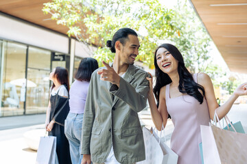 Asian young man and woman shopping goods outdoors in department store. 