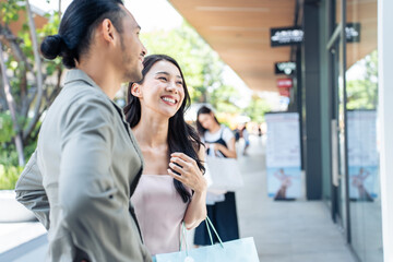 Asian young man and woman shopping goods outdoors in department store. 