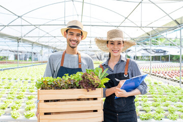 Portrait of Asian farmers couple work in vegetables hydroponic farm. 