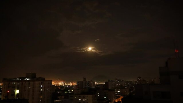 time lapse of clouds and moon over city