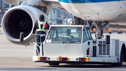 Towing of a passenger aircraft. The airplane nose, engine and towing truck close up.