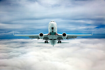 Front view of aircraft in flight. The passenger plane flies high above the clouds.