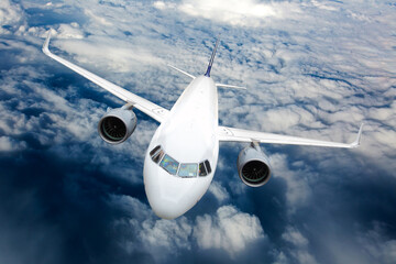 Fototapeta premium Passenger plane in flight. Aircraft fly high in the sky above the clouds. Front view. Right heeling.