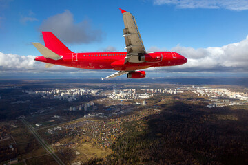 Red passenger plane in flight. The plane flies against a background of a city.