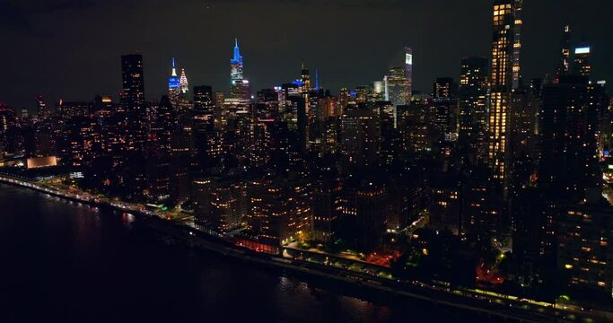 Night view of stunning New York from water. Lively traffic along the road at waterfront. Aerial view.