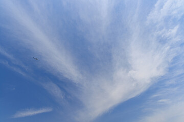 青空の白い雲に吸い込まれていく旅客機