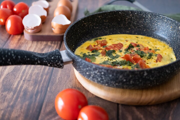 Close-up of scrambled eggs with tomatoes in a frying pan