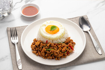Spicy minced pork pad kra pao, minced pork stir-fried with holy basil leaves, served with plain cooked rice and a fried egg, a popular Thai single dish served from street food carts to restaurants. - obrazy, fototapety, plakaty