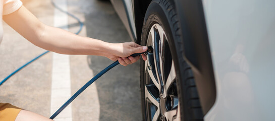 hand inflating tires of vehicle, checking air pressure and filling air on car wheel at gas station....