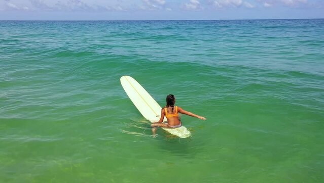 Aerial view group of Asian woman surfer paddling surfboard and riding the wave in the sea at tropical beach. Female friends enjoy outdoor activity lifestyle and water sport surfing on summer vacation