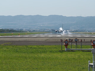 陽炎立つ滑走路に着陸したジェット機とタイヤからの煙