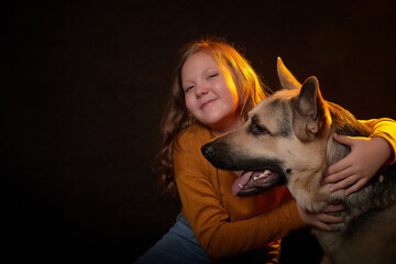 Small young girl with german shepherds in front of black background. Model posing in studio
