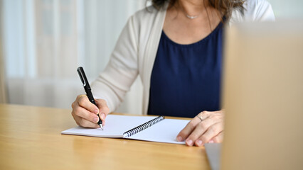 Senior retired aged asian woman writing something on her personal spiral notebook