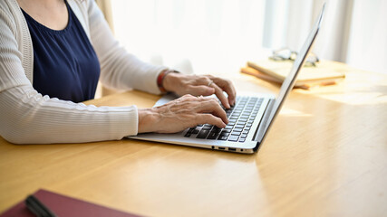 Cropped image of an asian middle aged woman using portable computer.