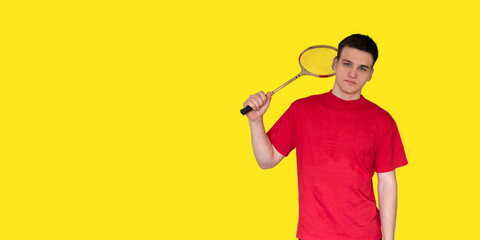 Portrait of an caucasian man holding a badminton racket on a yellow background