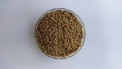 Pile of organic fresh horse gram bean seeds on glass bowl placed on white table background with...