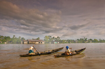 Two trader women, rowing a boat together