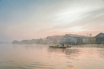 Two women rowing into the fog in Borneo